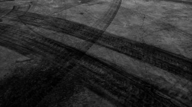 Close up black tire marks on cement floor. Abstract concrete texture in vintage style. Dark background for graphic design or wallpaper. Stains on the road surface caused by the wheels of the car.