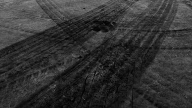 Close up black tire marks on cement floor. Abstract concrete texture in vintage style. Dark background for graphic design or wallpaper. Stains on the road surface caused by the wheels of the car.