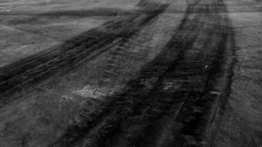 Close up black tire marks on cement floor. Abstract concrete texture in vintage style. Dark background for graphic design or wallpaper. Stains on the road surface caused by the wheels of the car.
