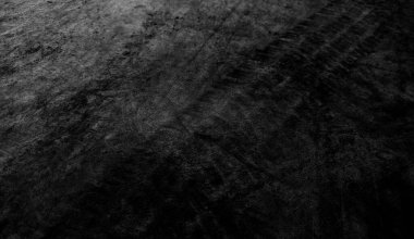 Close up black tire marks on cement floor. Abstract concrete texture in vintage style. Dark background for graphic design or wallpaper. Stains on the road surface caused by the wheels of the car.