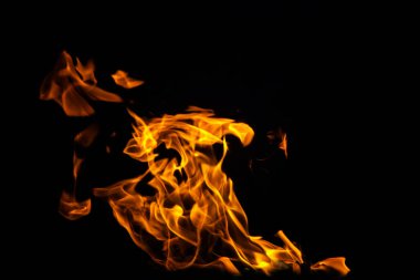 Grafik tasarımı ya da duvar kağıdı için yanan alevleri siyah arkaplanda kapat. Kırmızı ve sarı, ısı enerjisi gece boyunca yakıtı ateşliyor. Yemek pişirmek için kullanılan soyut ateş..