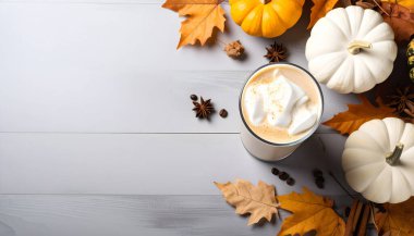 Balkabağı aromalı buzlu kahve. Soğuk köpük, tarçın, sonbahar yaprakları, ahşap masa..  