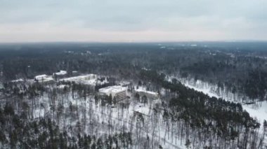 Buildings and houses in the middle of the forest in winter with snow. Shooting from a height on a quadcopter.