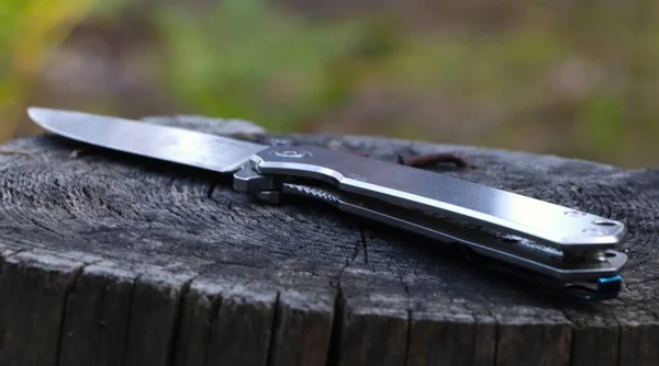 Close-up of a folding knife on a stump. Hobbies and outdoor recreation.