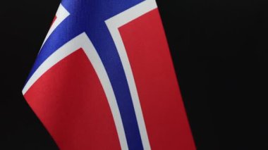 Siyah bir arkaplanda Norveç bayrağının yakın çekim döner görüntüsü.