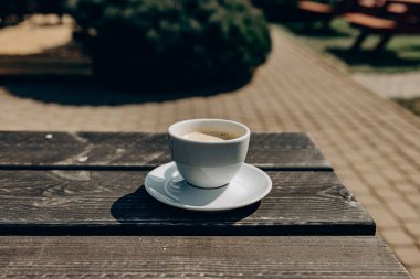 Bahçedeki ahşap masada kahve fincanı. Kahve fincanı ve tabağı peçeteye. Yıldız anason ve kahve çekirdekleri.