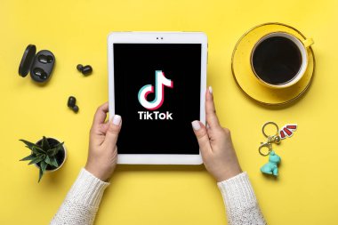 Bangkok, Tayland Ekim 2022 Smartphone Tik Tok uygulama simgesi, ekranda logo, kablosuz kulaklık, sarı masa şarj kapsülü Trendy sosyal medya ağı konsepti Flat Top view.