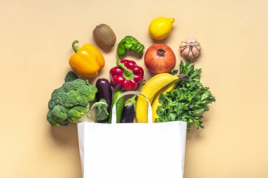 Çevre dostu, yeşil sebzeli, bej arka planda izole edilmiş çevre dostu kese kağıdı. Düz zemin, üst görünüm sıfır atık, plastiksiz konsept. Sağlıklı, temiz beslenme ve detoks, tarım kavramı..