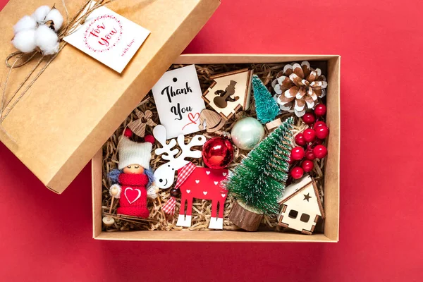 Handmade care package, seasonal gift box with toys, xmas decor on red table Personalized eco friendly basket for family, friends, girl for 24 December, Christmas, New Year day Flat lay.