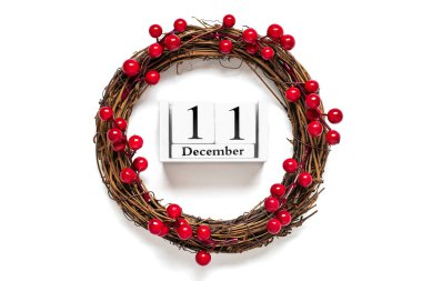 Kırmızı böğürtlenlerle süslenmiş Noel çelengi, 11 Aralık tarihli ahşap takvim beyaz arka planda izole edilmiş Noel hazırlığı konsepti, atmosfer dilekleri kartı, Noel çelengi düzleştirilmiş.