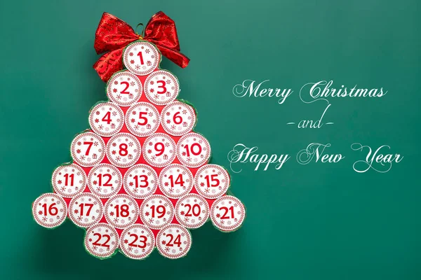 Advent calendar in shape of Christmas tree with numbers and ribbon instead of star, bokeh light on green background Xmas advent calendar concept Top view Flat lay.