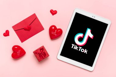 Bangkok, Tayland Aralık 2022 Smartphone Tik Tok uygulama simgesi, ekranda logo, pembe arka planda kırmızı kalpler modayı takip eden sosyal medya ağı konsepti.