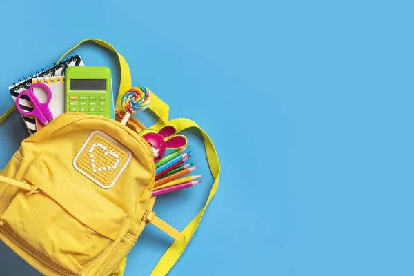 Back to school, education concept Yellow backpack with school supplies - notebook, pens, eraser rainbow, numbers isolated on blue background Top view Copy space Flat lay composition Banner.