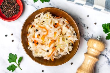 sour cabbage in wooden bowl pepper on white table Fermented vegetable concept Healthy food Top view.