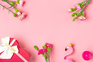 women's things - red gift box, flamingo, bouquet of carnation flowers, candle on pink background Flat lay Top view. Floral holiday card 8 March, Happy Valentine's day, Mother's day concept.
