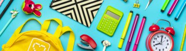 Okul ve ofis malzemelerinden çerçeve ataçlar, makas, dolma kalemler, keçeli kalemler, bileyici, hesap makinesi, zımba mavi arka planda izole edilmiş düz bir zemin, okula geri dön, eğitim kavramı.