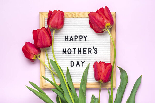 Доска из войлока с текстом С Днем Матери, букет из красных тюльпанов на розовом фоне Открытка на заднем плане.