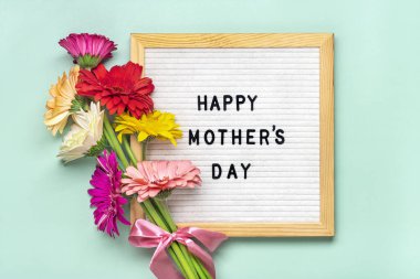 Mutlu Anneler Günü, yeşil arka plan tebrik kartı üzerinde renkli gerberas buketi Düz üst görünüm yatıyordu.