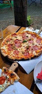 Bir kafede sosisli ve zeytinli büyük pizza.