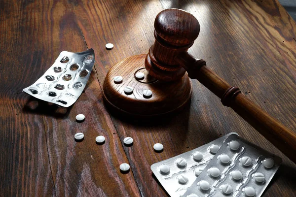 Law in medicine. Judge gavel and pills on a wooden background. Concept of medical law and medical crimes