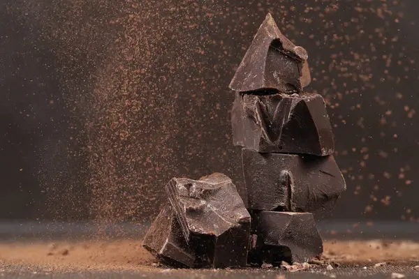 Broken dark chocolate and chocolate flakes on a wooden table
