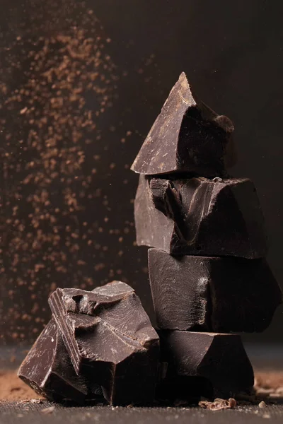 Broken dark chocolate and chocolate flakes on a wooden table