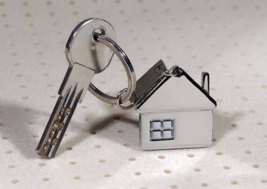 Soyut arka planda gümüş anahtarlı ev sembolü. Emlak kavramı