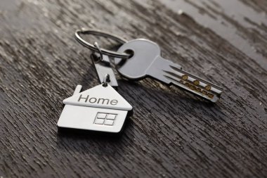 Soyut arka planda gümüş anahtarlı ev sembolü. Emlak kavramı