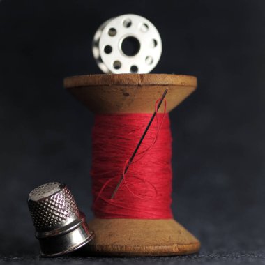 Ahşap, kırmızı iplik, iğne, metal yüksük, soyut arka grup.