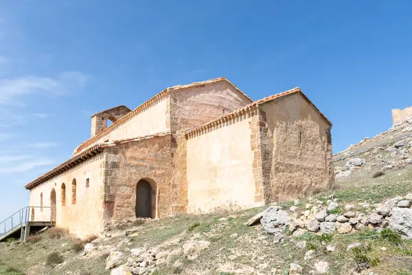 stock image Romanesque hermitage of San Miguel in Gormaz with the caliphal fortress in the background on a sunny day.