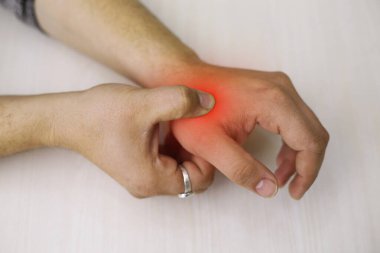 A young man feeling pain in his hand at home. Healthcare and medical concept.