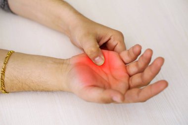 A young man feeling pain in his hand at home. Healthcare and medical concept.