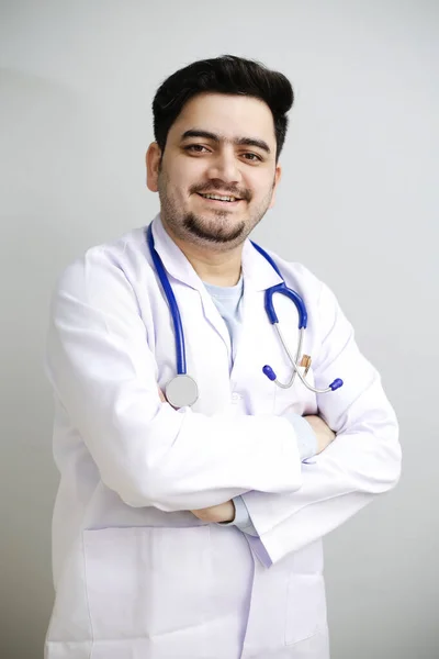 A young doctor is standing with crossed arms and smiling.