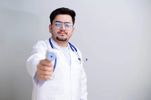 Ένας Νεαρός Γιατρός Στέκεται Και Κρατά Ψηφιακό Θερμόμετρο Στο Χέρι — Φωτογραφία Αρχείου