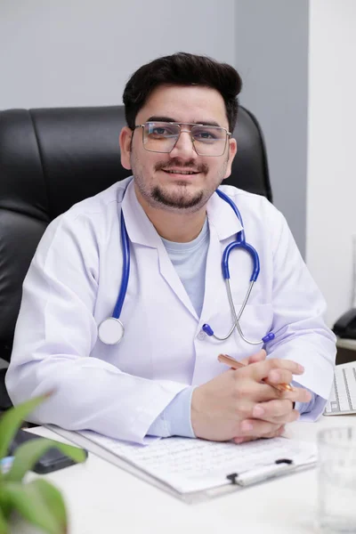 Joven Médico Está Sentado Clínica Sonríe —  Fotos de Stock
