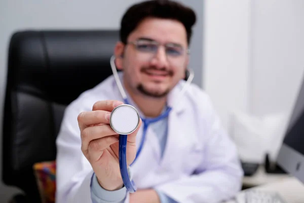 Mladý Doktor Sedí Klinice Drží Stetoskop Ruce — Stock fotografie