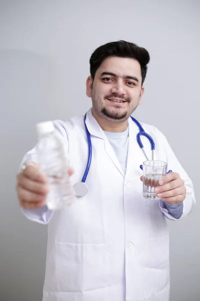 Młody Lekarz Stoi Szklanką Wody Jednej Ręce Butelką Wody Drugiej — Zdjęcie stockowe