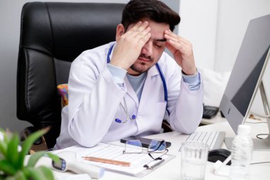 Genç bir doktor klinikte oturuyor ve stres altında..
