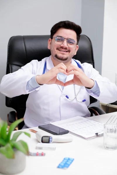 Mladý Doktor Sedí Klinice Dělá Srdce Rukou Usmívá — Stock fotografie