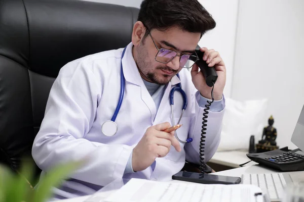 Młody Lekarz Siedzi Klinice Rozmawia Przez Telefon Używa Komórki — Zdjęcie stockowe
