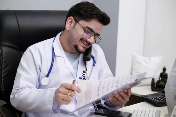 Ein Junger Arzt Sitzt Der Klinik Telefoniert Und Liest Bericht — Stockfoto