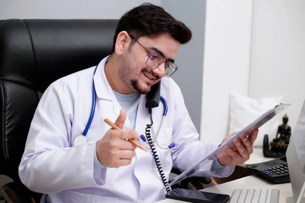 Młody Lekarz Siedzi Klinice Rozmawia Przez Telefon — Zdjęcie stockowe