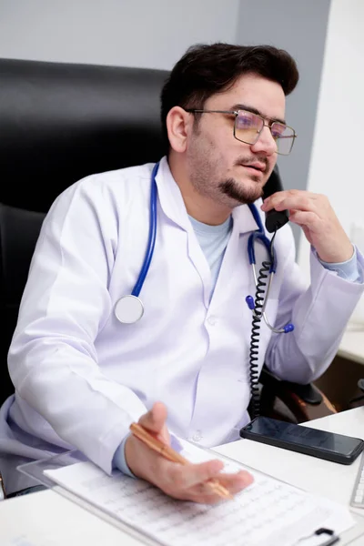Jovem Médico Está Sentado Clínica Falando Por Telefone — Fotografia de Stock