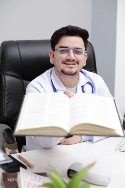 一位年轻的医生正坐在诊所里 手里拿着日记 — 图库照片