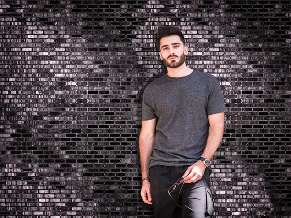 A man standing in front of a brick wall