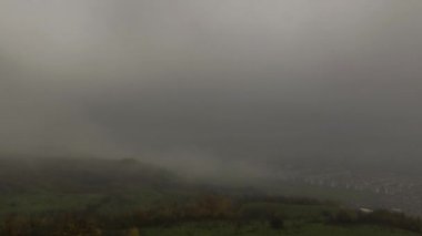 Ladin ormanının üzerinde sis bulutları ve kentsel alandaki küçük bir köy. Sonbahar günü