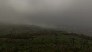 Ladin ormanının üzerinde sis bulutları ve kentsel alandaki küçük bir köy. Sonbahar günü