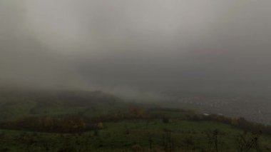 Ladin ormanının üzerinde sis bulutları ve kentsel alandaki küçük bir köy. Sonbahar günü