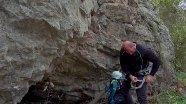 Orta yaşlı bir adam ferrata / klettersteig aracılığıyla güneşli bir sonbahar gününde bir kayaya tırmandıktan sonra kendini donatıyor.