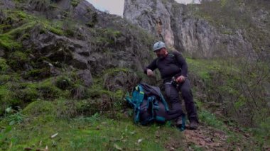 Orta yaşlı bir adam ferrata / klettersteig üzerinden güneşli bir sonbahar gününde kayaya tırmandıktan sonra elma yiyor.